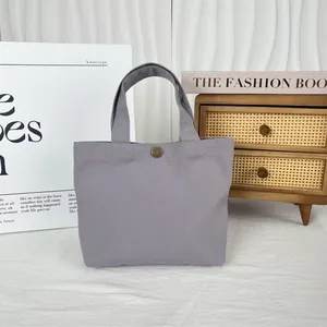Close-up detail of a minimalist gray canvas tote bag featuring a vintage metal button