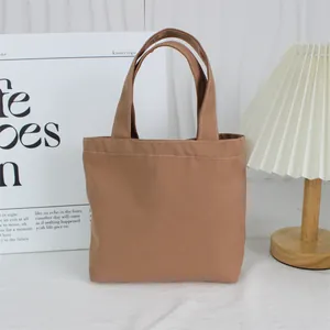 Minimalist brown canvas lunch bag shown with clean desk setup and pleated lamp.