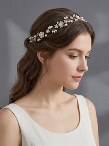 Dettaglio di una fascia da sposa fatta a mano con perle e fiori su una modella.