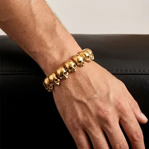 Close-up of a gold-toned titanium steel men's bracelet with detailed skull links.