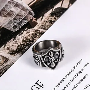 Bague bouclier vintage pour homme en acier titane avec fleur de lys en relief chic.
