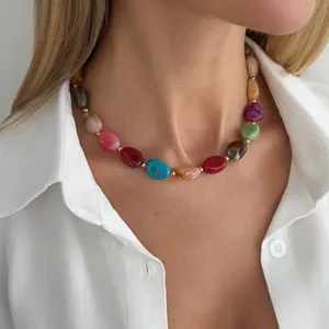 Detailed view of colorful irregular resin bead necklace worn on neck with white shirt
