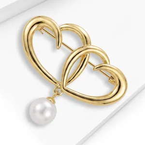 Close-up of gold interlocking heart brooch with a white pearl pendant detail.