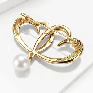 Detailed macro view of an elegant gold heart brooch with a hanging white pearl.