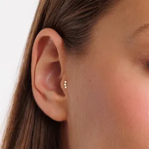 Macro view of delicate three-stone zircon tragus piercing stud in gold-plated S925 silver