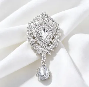 Détail de la broche couronne de luxe avec strass et pendentif en goutte d'eau.
