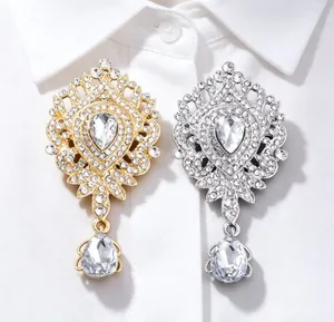 Vue détaillée de broches couronne de luxe en strass doré et argenté sur chemise blanche.