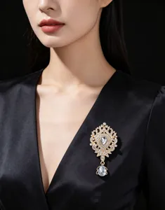 Exquise broche couronne dorée avec strass scintillants et pendentif goutte