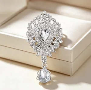 Détail d'une broche couronne de luxe ornée de cristaux avec un pendentif en goutte