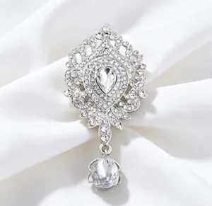 Gros plan d'une luxueuse broche en forme de couronne ornée de strass et d'un pendentif