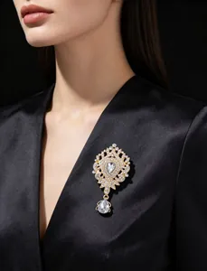 Élégante broche couronne en cristal doré avec pendentif goutte sur blazer en satin.
