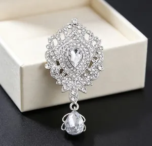 Broche couronne vintage de luxe ornée de strass clairs et d'un élégant pendentif goutte.
