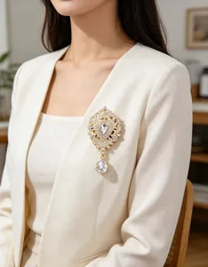 Broche couronne luxueuse avec strass et un pendentif goutte sur un blazer blanc.
