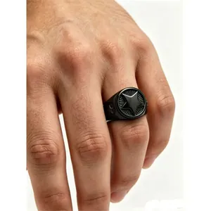 Close-up of black titanium steel men's signet ring with star motif on finger.