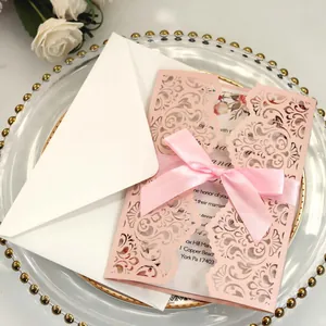 Elegant laser-cut light pink wedding invitation card with pink ribbon and white envelope