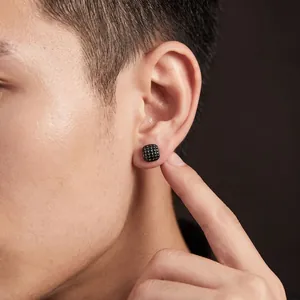 Detailed view of a black square grid textured stud earring worn on a male model ear.