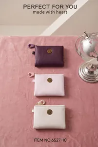 Three minimalist PU leather coin purses in various colors on pink velvet background
