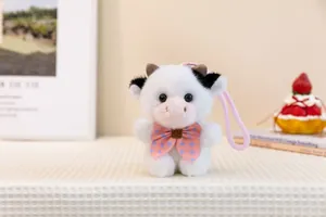 Detailed view of cute plush cow keychain with pink polka-dot bow tie and strap