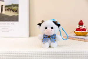Close-up of cute plush cow keychain with blue polka dot bow tie and hanging strap