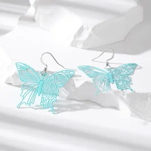 Cyan butterfly hollow-out drop earrings with elegant floral pattern on rocks
