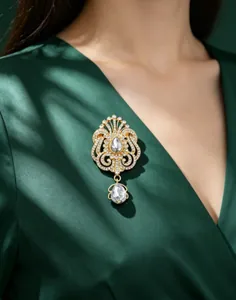 Détail élégant d'une broche couronne en strass dorée sur une robe vert foncé satinée
