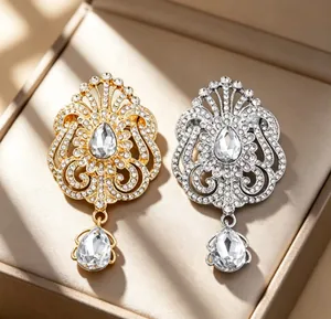 Détail rapproché de broches couronne en forme de goutte en or et argent avec strass scintillants