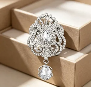 Détail d'une broche couronne argentée vintage avec des strass brillants en forme de goutte