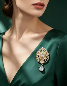 Gros plan sur une broche couronne dorée avec goutte de cristal sur une robe