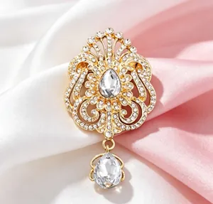 Vue rapprochée d'une broche goutte dorée avec motif couronne et strass blancs.
