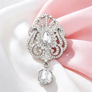 Broche goutte élégante argentée avec des strass étincelants sur tissu doux
