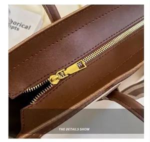 Close-up view of a smooth gold metal zipper and stitching on a brown leather tote bag