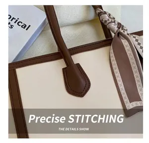 Detailed view of the precise stitching and brown handle trim on a cream fashion tote bag