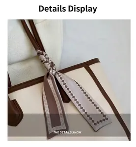 Close-up of a stylish tote bag handle with a decorative patterned silk scarf detail.