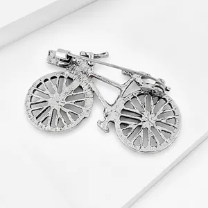 Macro detail of a vintage silver bicycle brooch pin featuring an antique metal finish