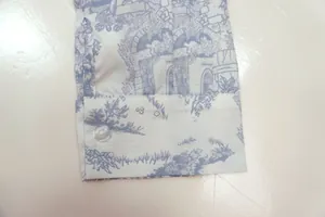 Detail shot of shirt cuff with blue landscape print and transparent button.