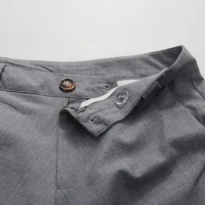 Close-up detail of the elegant grey pleated skirt's adjustable waistband and button.