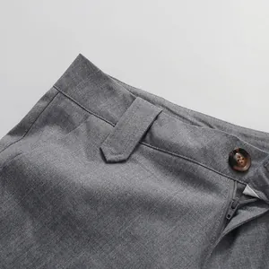 Detailed view of the gray pleated skirt waistband featuring a button and zipper