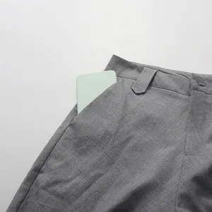 Detailed view of the functional side pocket on a grey pleated straight skirt with phone