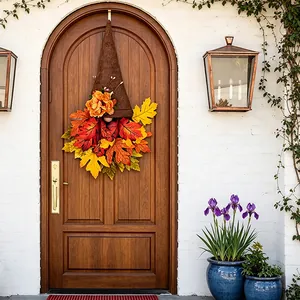 Decorative autumn gnome wreath with red and yellow maple leaves hanging on front door