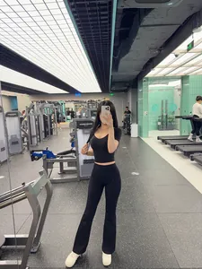 Modella asiatica indossa pantaloni yoga svasati a vita alta neri in una palestra