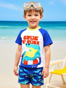 Detail shot of boy wearing a two-piece blue and white crocodile print swimwear set on a sunny beach