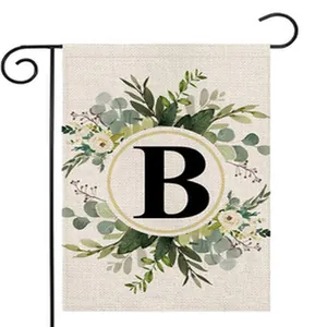 Detailed close-up of garden flag featuring floral wreath and monogram letter B design
