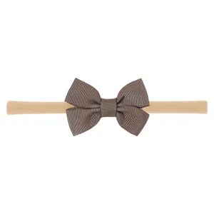 Elegante lazo de cinta otomán marrón en una diadema de nailon beige para bebés