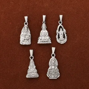 Five detailed silver Buddha and Guanyin Bodhisattva pendants on brown textured surface
