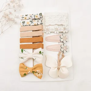 Gros plan d'un ensemble de barrettes en tissu pour enfants avec motifs floraux et papillon.
