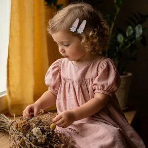 Jolie petite fille portant des barrettes à fleurs brodées roses et une robe rose