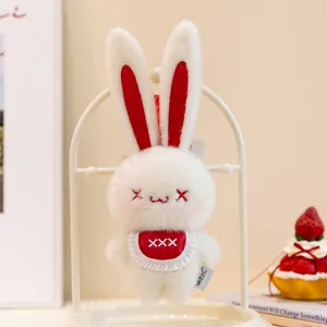 Detail view of a cute white plush bunny keychain with red bib and strawberry prop