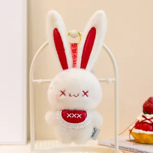 Detailed view of a white plush bunny keychain with red cross eyes and cute bib