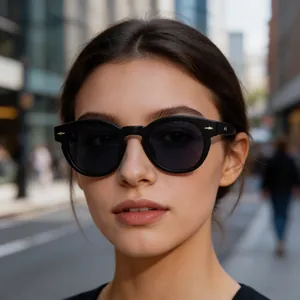 Close-up view of stylish black oval sunglasses featuring gold arrow hardware on a model