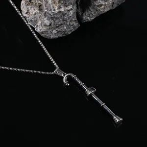 Gros plan détaillé d'un collier pendentif canne argenté vintage avec des textures gravées.